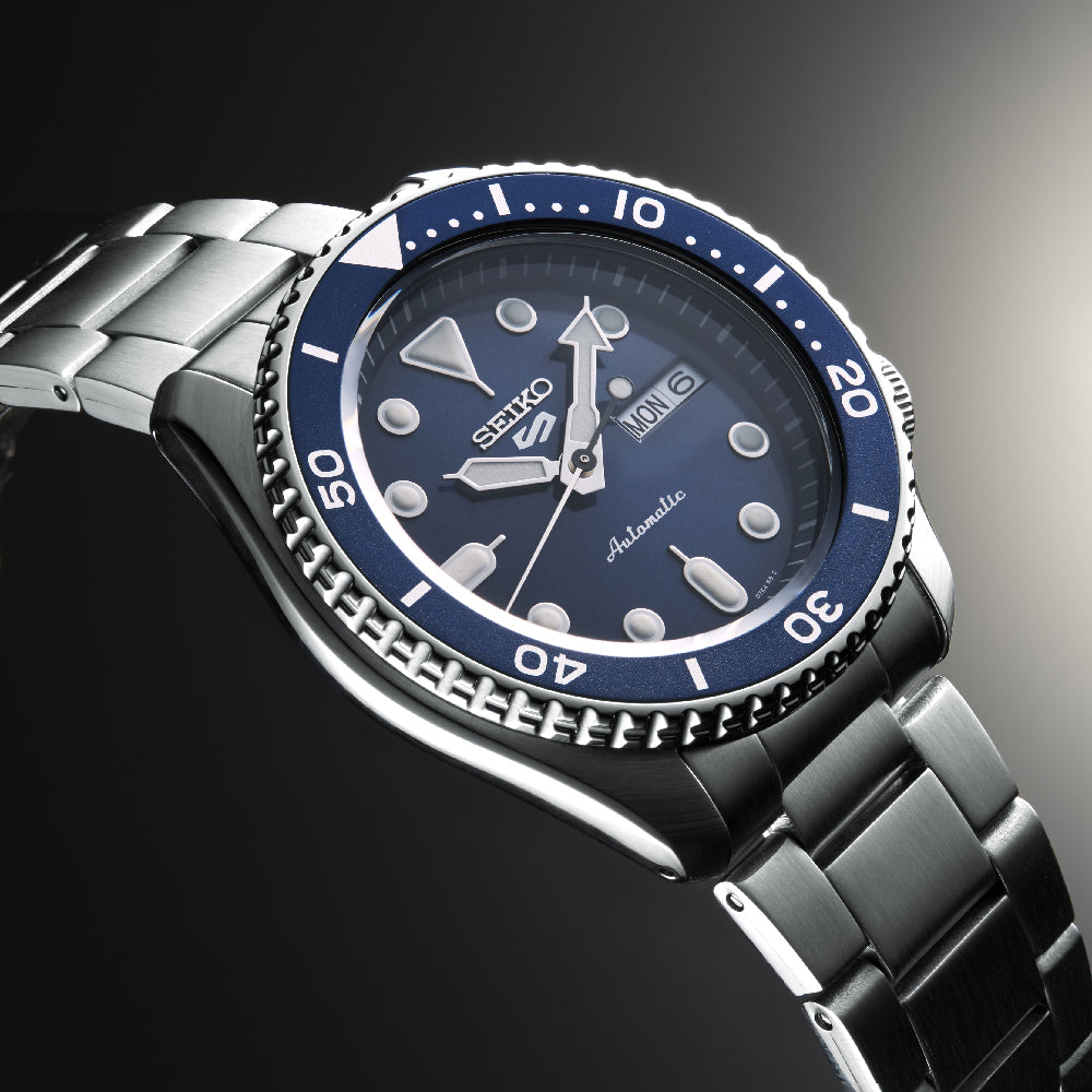 Ontdek het verfijnde Seiko 5 Sports herenhorloge SRPD51K1 van Seiko, met een roestvrijstalen ontwerp met een blauwe bezel en wijzerplaat, lichtgevende uurmarkeringen, dag-datumweergaven en een automatisch uurwerk. De draaiende bezel met genummerde markeringen verbetert dit elegante uurwerk.