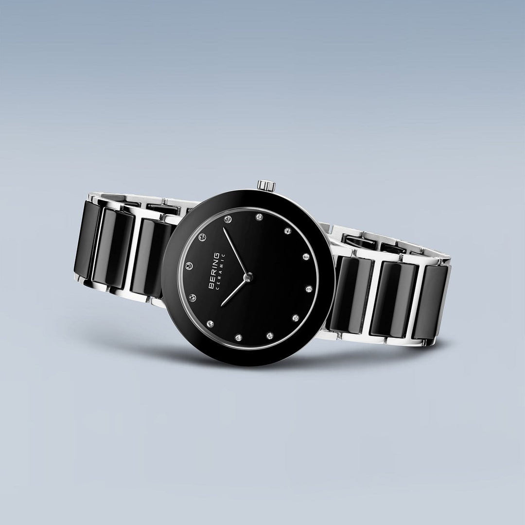 Het Bering 11435-749 dameshorloge heeft een quartz-uurwerk, een zwarte wijzerplaat met zilveren accenten en een glanzend zwarte band met zilveren schakels. Het minimalistische ontwerp heeft geen cijfers, tegen een gradiëntblauwe achtergrond en het beschikt over duurzaam saffierglas voor blijvende elegantie.