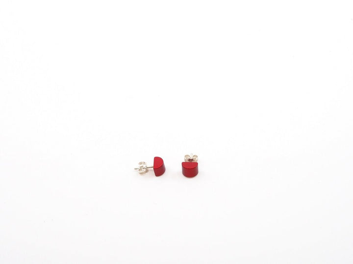 Een paar kleine, rode, halfronde oorknopjes van Otra Cosas Gekleurde half ronde oorbellen rood lijn, met moderne stijl met geanodiseerde aluminium achterkanten, weergegeven op een effen witte achtergrond.
