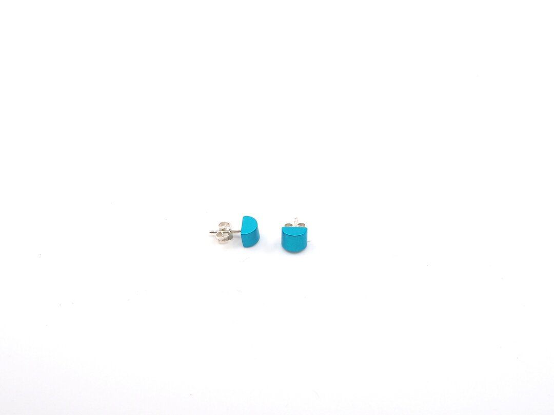 Een paar kleine, ronde turquoise oorbellen van Otra Cosa met de naam Gekleurde half ronde oorbellen turquoise zijn gemaakt van geanodiseerd aluminium met zilveren achterkanten, afgebeeld op een effen witte achtergrond.