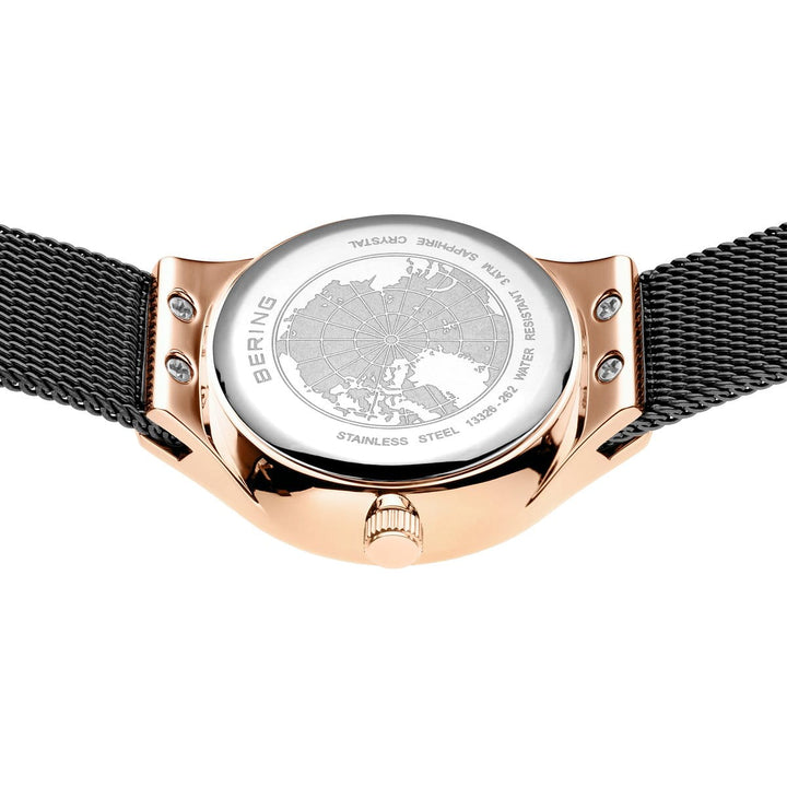 Een close-up van het Bering 13326-262-GWP horloge toont de kast van roestvrij staal met gouden afwerking, met de inscripties Bering, Sapphire Crystal en Stainless Steel. De achterkant is voorzien van een kaartontwerp, terwijl een mesh-band het elegante Quartz-uurwerk complementeert.