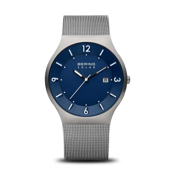 Reloj de esfera azul con correa de malla de acero inoxidable y detalles plateados.