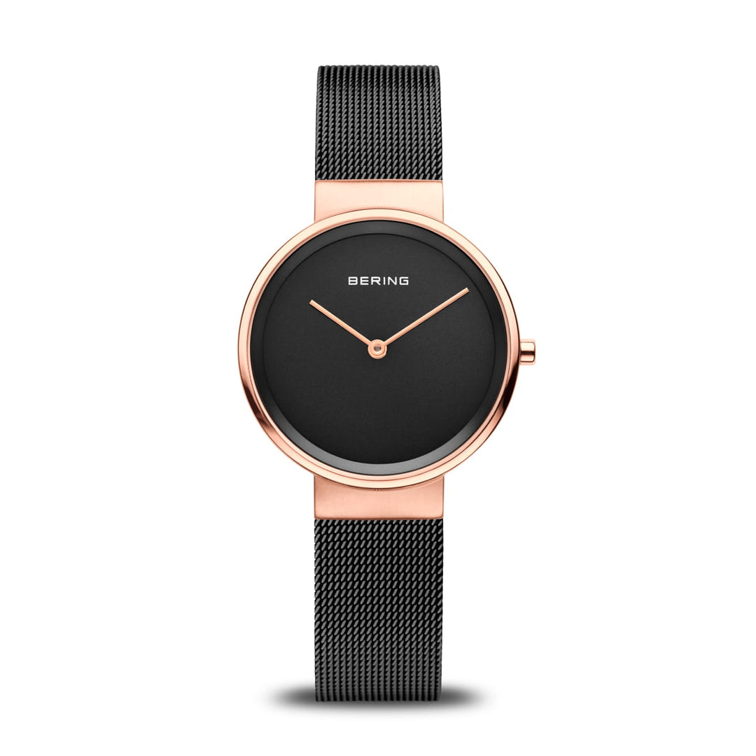 Dit minimalistische Bering Dameshorloge, model 14531-166, heeft een ronde zwarte wijzerplaat met een slanke goudkleurige lunette, quartz uurwerk, twee eenvoudige gouden wijzers en een fijne zwarte mesh band. Bering wordt elegant weergegeven op de roestvrijstalen kast.