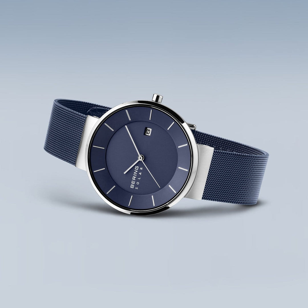 Ontdek het elegante Bering polshorloge 14639-307: een strak horloge met een donkerblauwe wijzerplaat, zilveren uurmarkeringen, datumvenster en eenvoudige wijzers onder robuust Saffierglas. De grijsblauwe meshband belichaamt tijdloze verfijning.