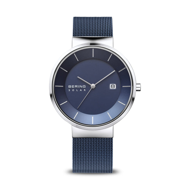 Het Bering 14639-307 Herenhorloge heeft een strakke blauwe wijzerplaat met zilveren kast, beschermd door Saffierglas. Het bevat minimale witte uurmarkeringen, een datumvenster op 3 uur, Bering Solar-branding en een blauwe meshband in een moderne, minimalistische stijl.
