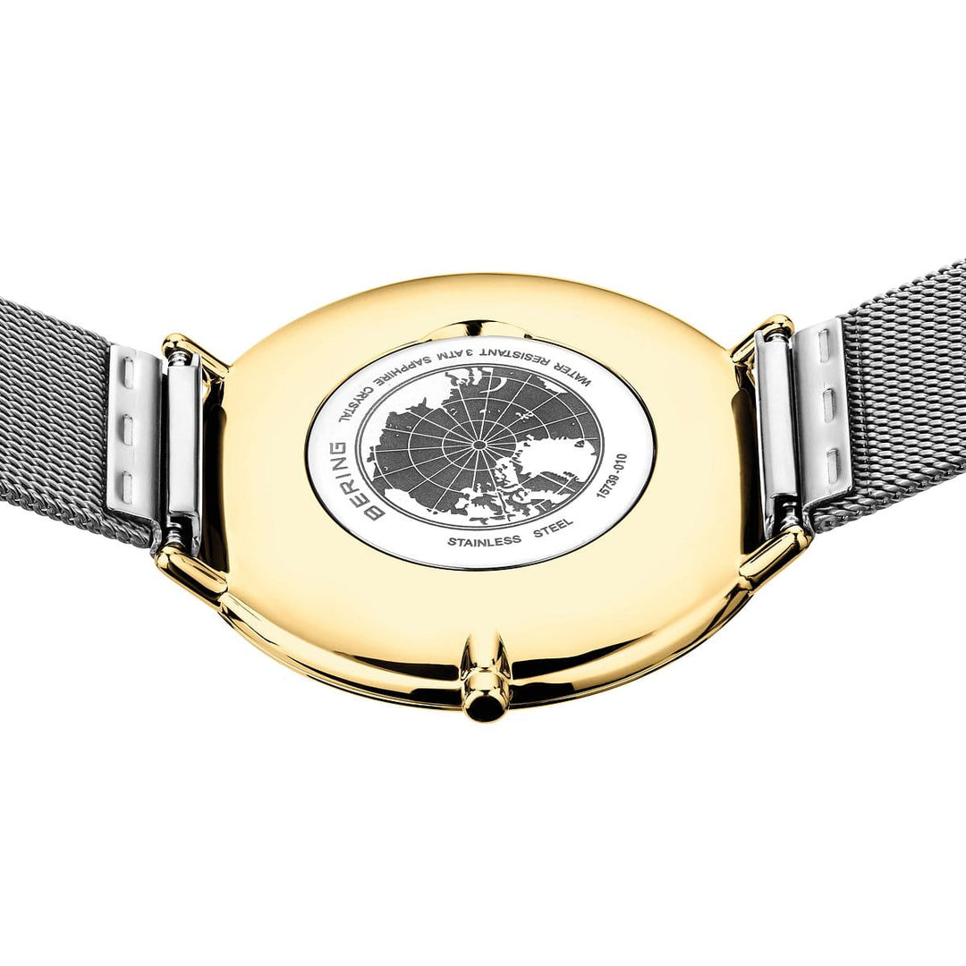 De afbeelding toont de achterkant van het Bering dameshorloge model 15739-010 met een roestvrijstalen kast en mesh band, met een elegant gegraveerd wereldkaartontwerp en teksten met onder meer Bering, Concepts en Stainless Steel, wat een tijdloze elegantie uitstraalt.