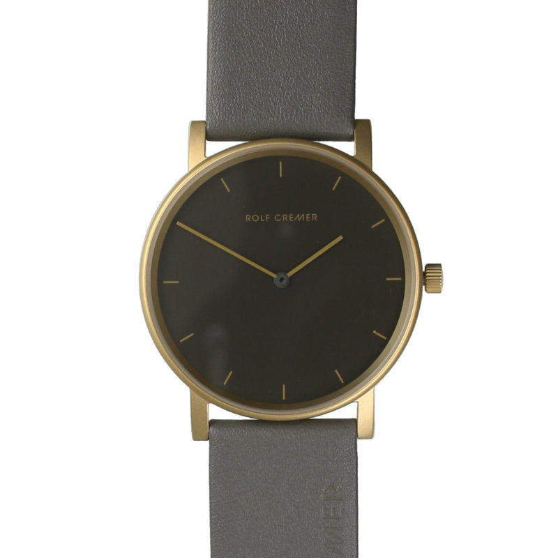 Reloj con caja dorada, esfera gris oscuro y correa de cuero gris.