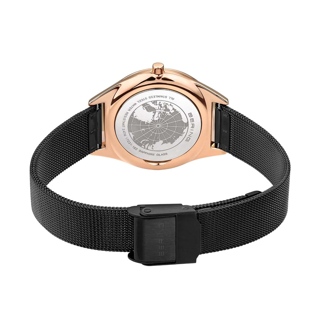 De afbeelding toont het Bering 17031-162 Unisex Quartz horloge van de achterkant, met een ronde roségouden roestvrijstalen kast en zwarte mesh band. Het krasbestendige saffierglas toont een gegraveerde wereldkaart in zilver.