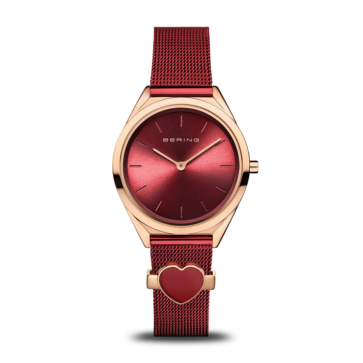 Reloj con esfera roja, caja dorada y correa de malla roja con un corazón decorativo.