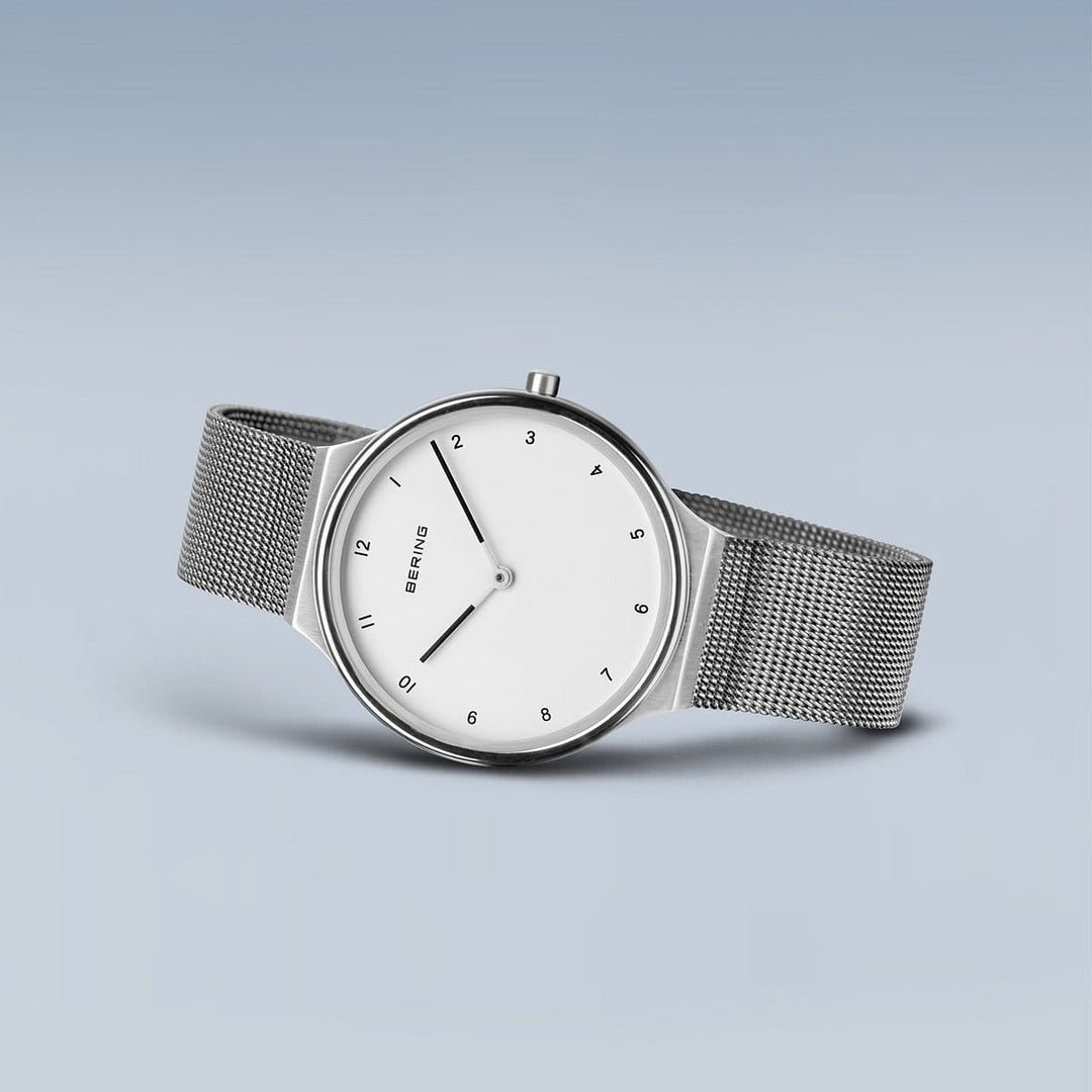 Het Bering dameshorloge 18434-004 is minimalistisch met een witte wijzerplaat, zwarte uurmarkeringen en wijzers. Het heeft een zilveren kast met quartz uurwerk, mesh zilveren band, gradiënt blauwe achtergrond, versterkt door duurzaam saffierglas.