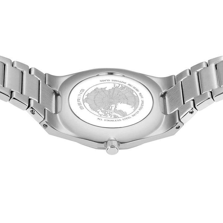 De afbeelding toont de achterkant van een roestvrijstalen bering dames horloge zilveren dial - 19632-700 van Bering, met een gegraveerde wereldkaart en kompas. Dit elegante horloge heeft saffierglas, een kwartsuurwerk, metalen band, zichtbare kroon en randtekst met details over materialen en specificaties.