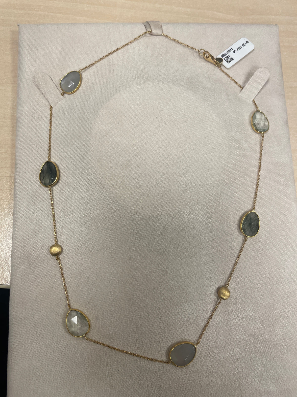 Collar dorado con piedras semipreciosas en forma ovalada y detalles en tonos verdes y transparentes.