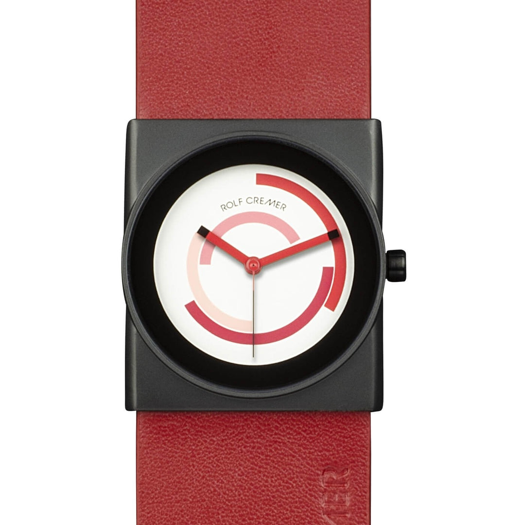 Het Rolf Cremer Horloge 507403 Alvo heeft een unisex vierkante, zwarte kast en een opvallende rode leren band, met een minimalistische wijzerplaat met een rood cirkelvormig patroon en zwarte wijzers op een witte achtergrond. Het geheel wordt aangestuurd door een betrouwbaar quartz-uurwerk.