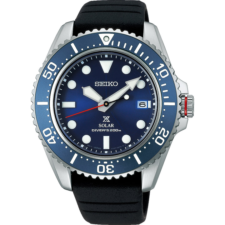Deze afbeelding toont het Seiko Prospex heren horloge SNE593P1, een duikhorloge met een opvallende blauwe wijzerplaat en lunette, grote witte markeringen en een datumvenster op 3 uur. Het combineert een roestvrijstalen kast met een zwarte rubberen band en solar uurwerk voor precisie tot 200 meter.