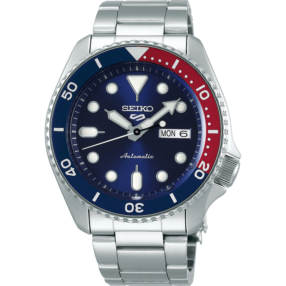 Reloj de hombre Seiko 5 Sports con esfera azul, bisel rojo y plata, y correa de acero inoxidable.