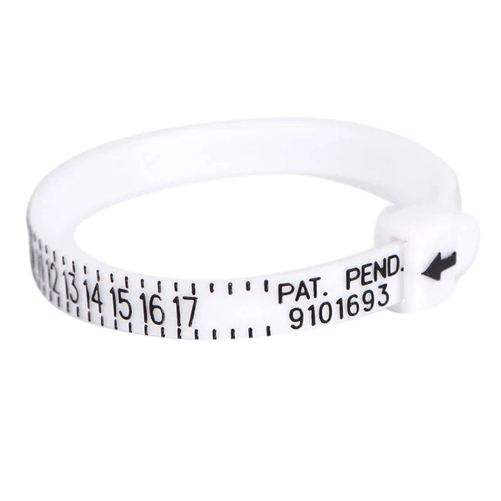 De Pas ring voor de perfecte ring maat van Juwelier van der Kooij is een witte, verstelbare ringmaatmeter van kunststof, met zwarte cijfers van 0-17, een kleine zwarte pijl en PAT. PEND. 9101693 bij de sluiting voor nauwkeurige metingen, elke keer weer.