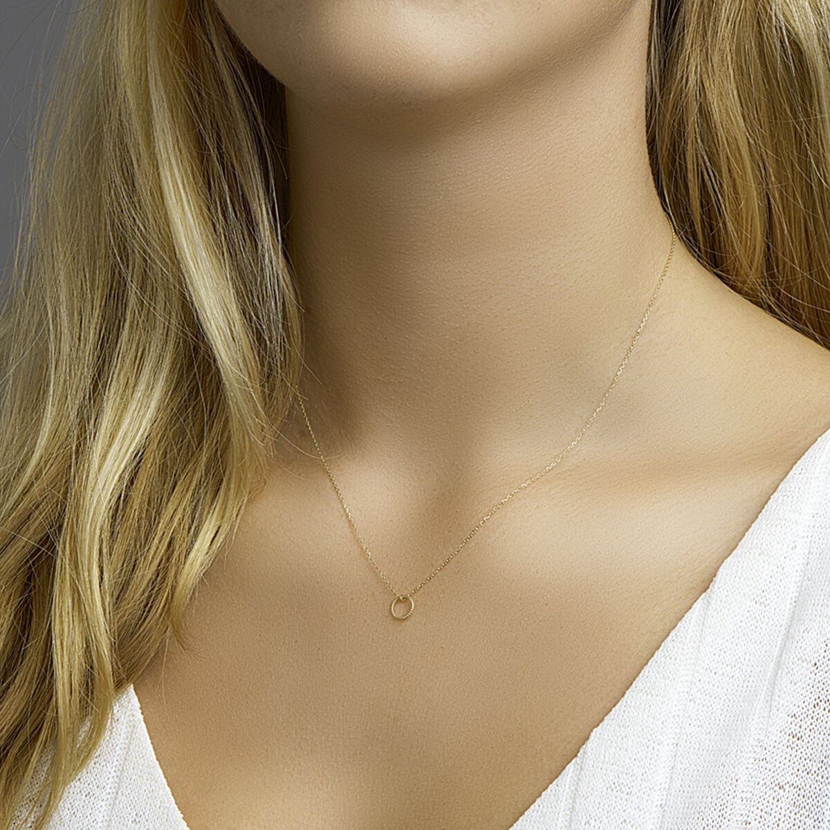 Close-up van een vrouw met het Van der Kooij Collectie collier rondje 40-42-44 cm in 14K geelgoud, gestyled met lang blond haar en een wit topje met structuur - een elegant dames sieraad voor elke gelegenheid.