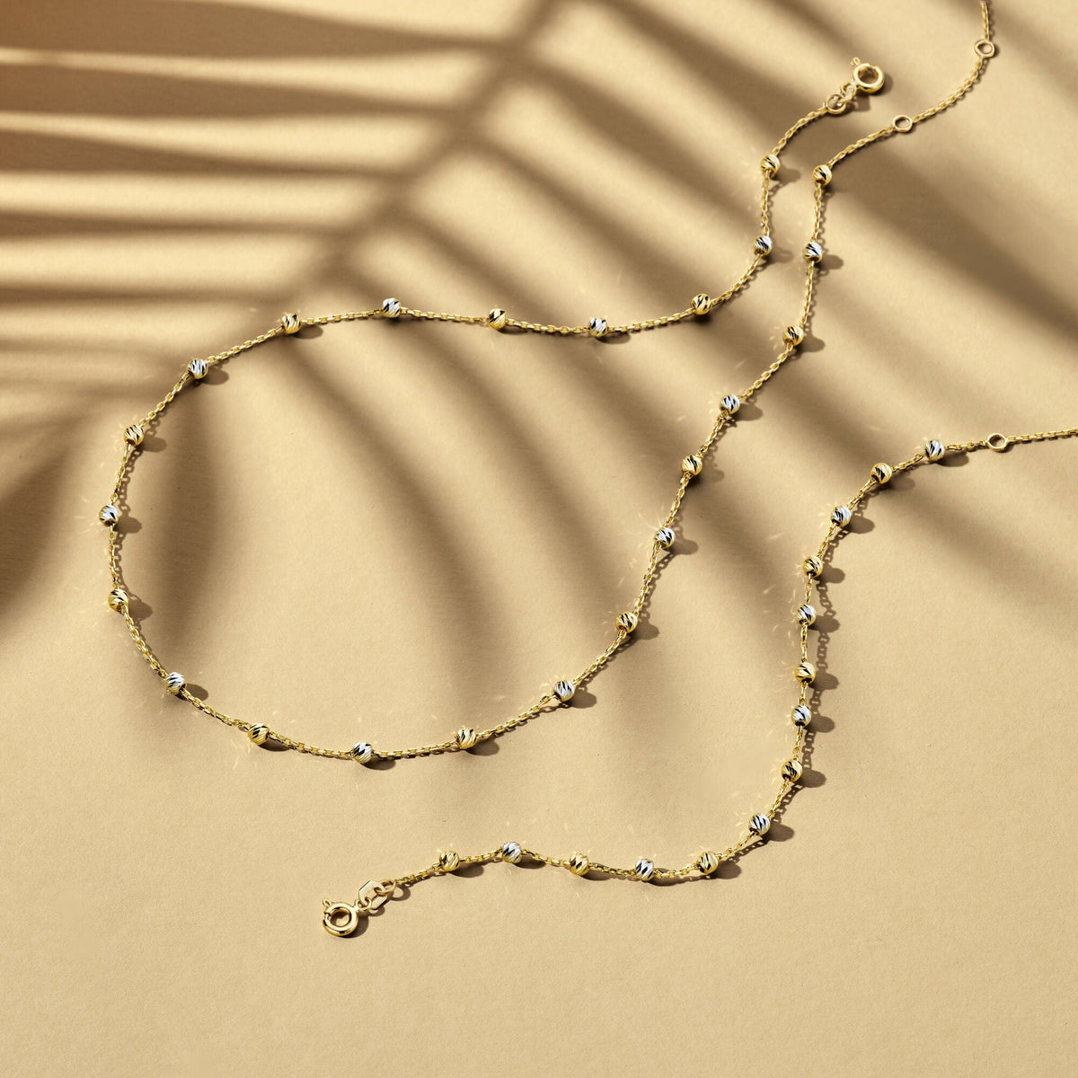 De Van der Kooij Collectie Gouden armband dames bolletjes gediamanteerd 14K bicolor, met wit- en geelgoud details en diamanten accenten, rust elegant op een tan oppervlak voor een verfijnde look.