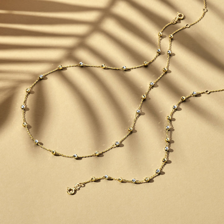 De Van der Kooij Collectie Gouden armband dames bolletjes gediamanteerd 14K bicolor, met wit- en geelgoud details en diamanten accenten, rust elegant op een tan oppervlak voor een verfijnde look.