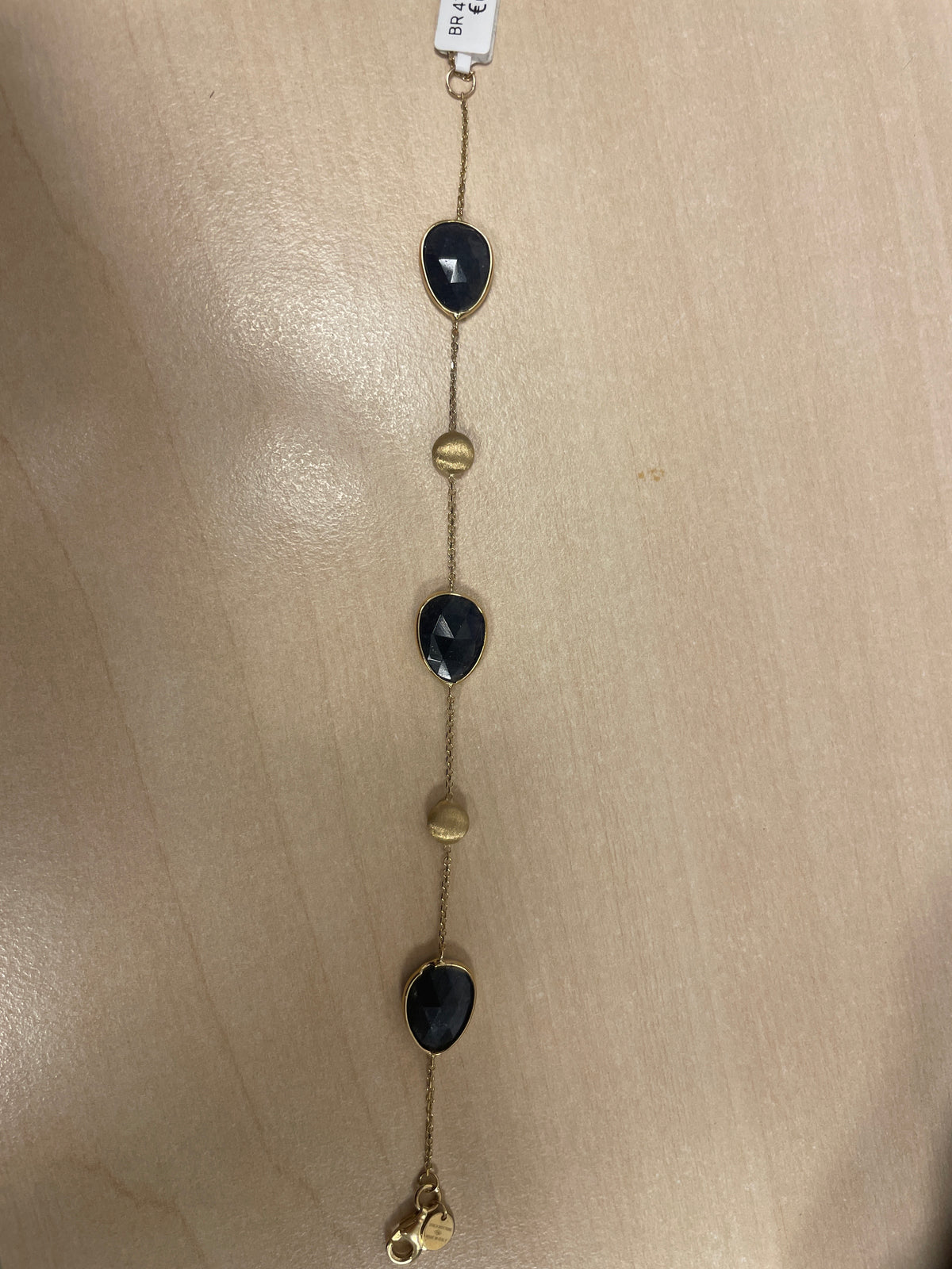 Pulsera dorada con piedras negras y detalles en dorado.
