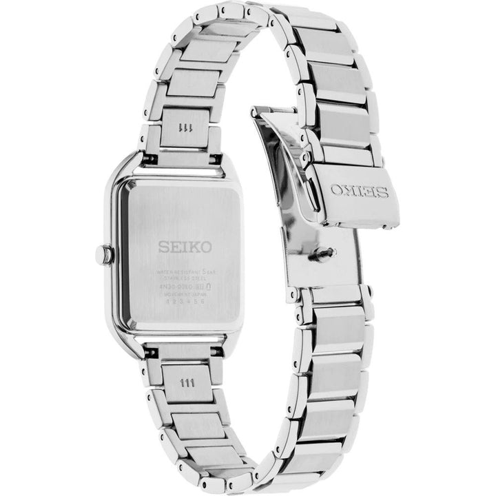 Het Seiko dameshorloge SWR075P1, een zilveren horloge met een verstelbare roestvrijstalen band, is vanaf de achterkant te zien, waarbij de sluiting en het gegraveerde Seiko-logo op de kast en sluiting te zien zijn, samen met een klein knoopje aan de zijkant.