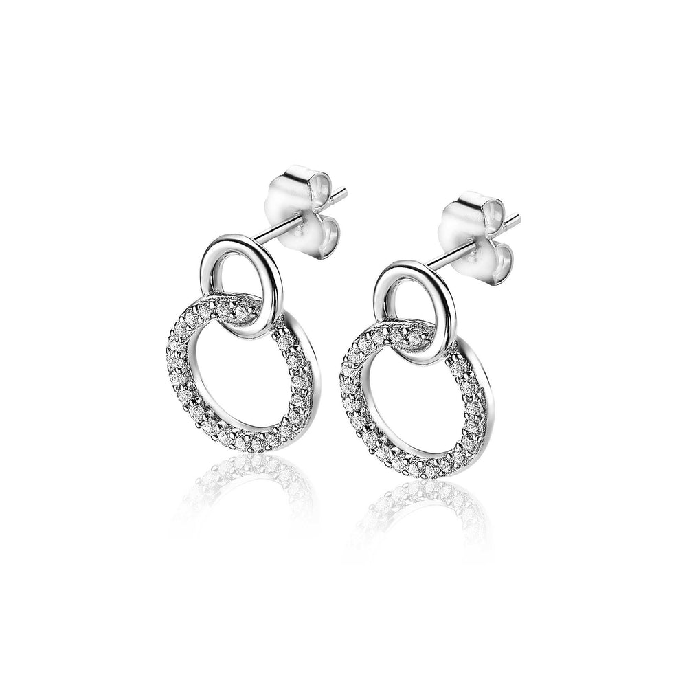 Zinzi Oorbellen Zilver Zio1782: Elegante zilveren oorbellen van Zinzi met twee in elkaar grijpende cirkels - één gepolijst, één versierd met fonkelende steentjes - tegen een witte achtergrond.