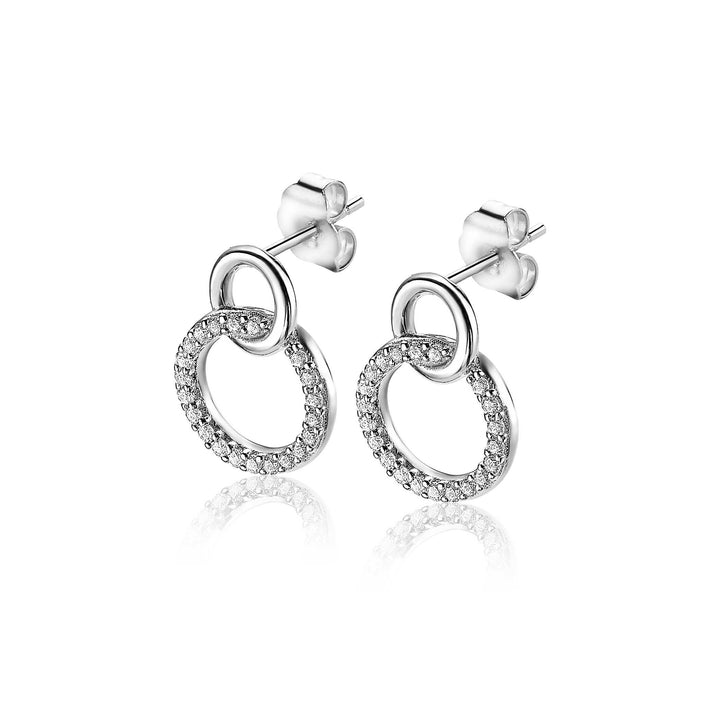 Zinzi Oorbellen Zilver Zio1782: Elegante zilveren oorbellen van Zinzi met twee in elkaar grijpende cirkels - één gepolijst, één versierd met fonkelende steentjes - tegen een witte achtergrond.