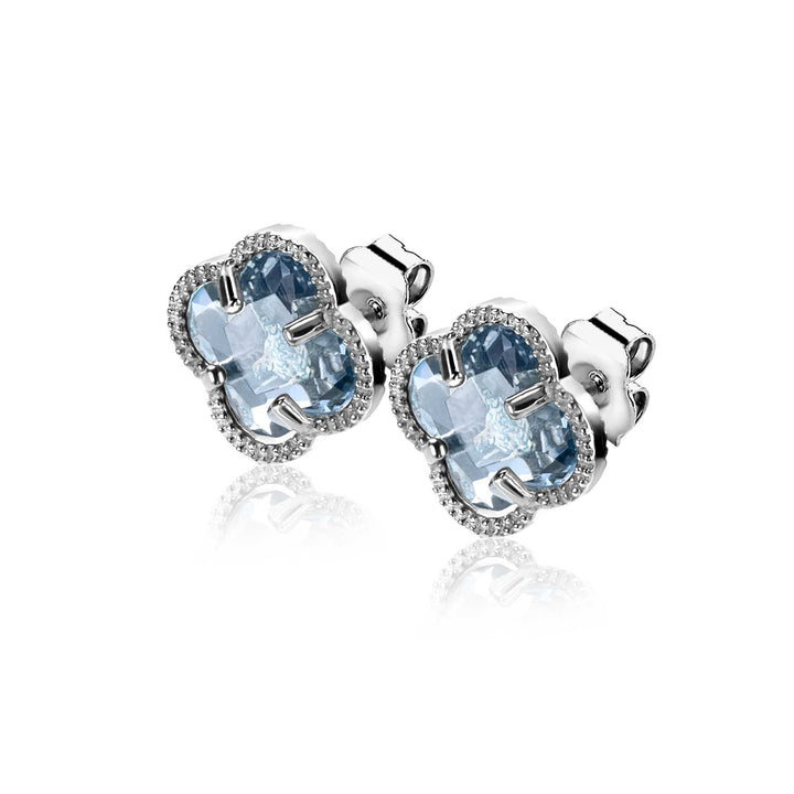 Een paar Zinzi Oorbellen Zilver ZIO2663B van Zinzi, met lichtblauwe klavervormige stenen omringd door heldere kristallen, tegen een witte achtergrond.