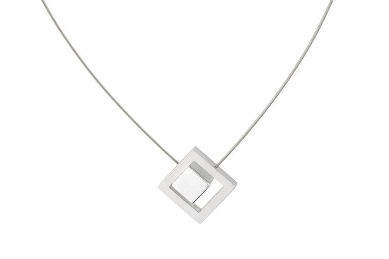 Collar con colgante cuadrado en forma de cubo, acabado en plata.