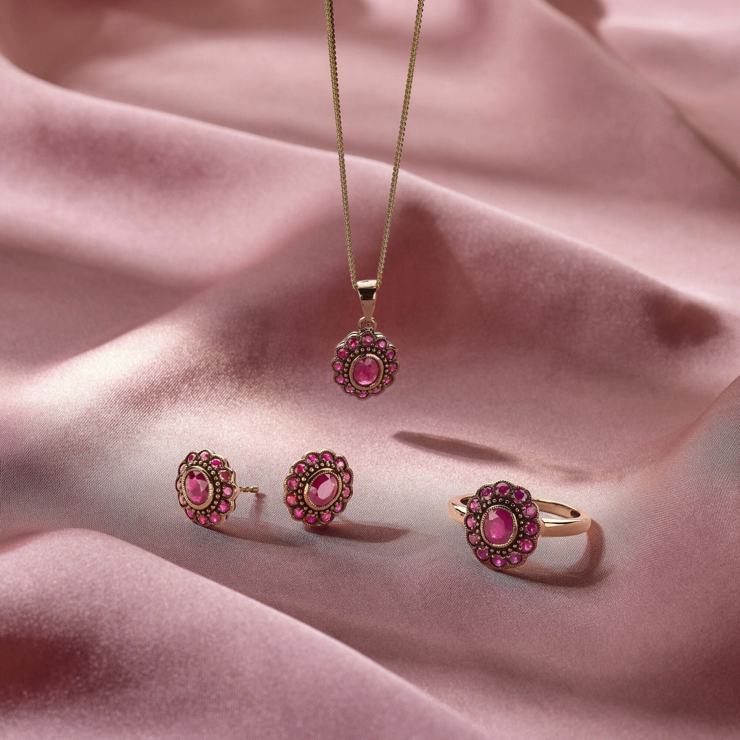 De Van der Kooij Collectie ring robijn 14K geelgoud schittert met ronde roze edelstenen en delicate roze accenten, elegant gepresenteerd op zachte, zijdeachtige roze stof.