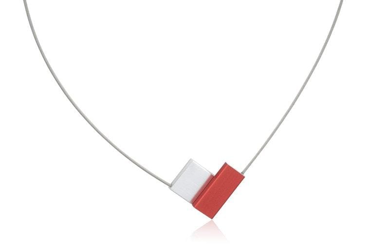 Collar en forma de V con detalles rojos y blancos, sobre un cordón delgado.