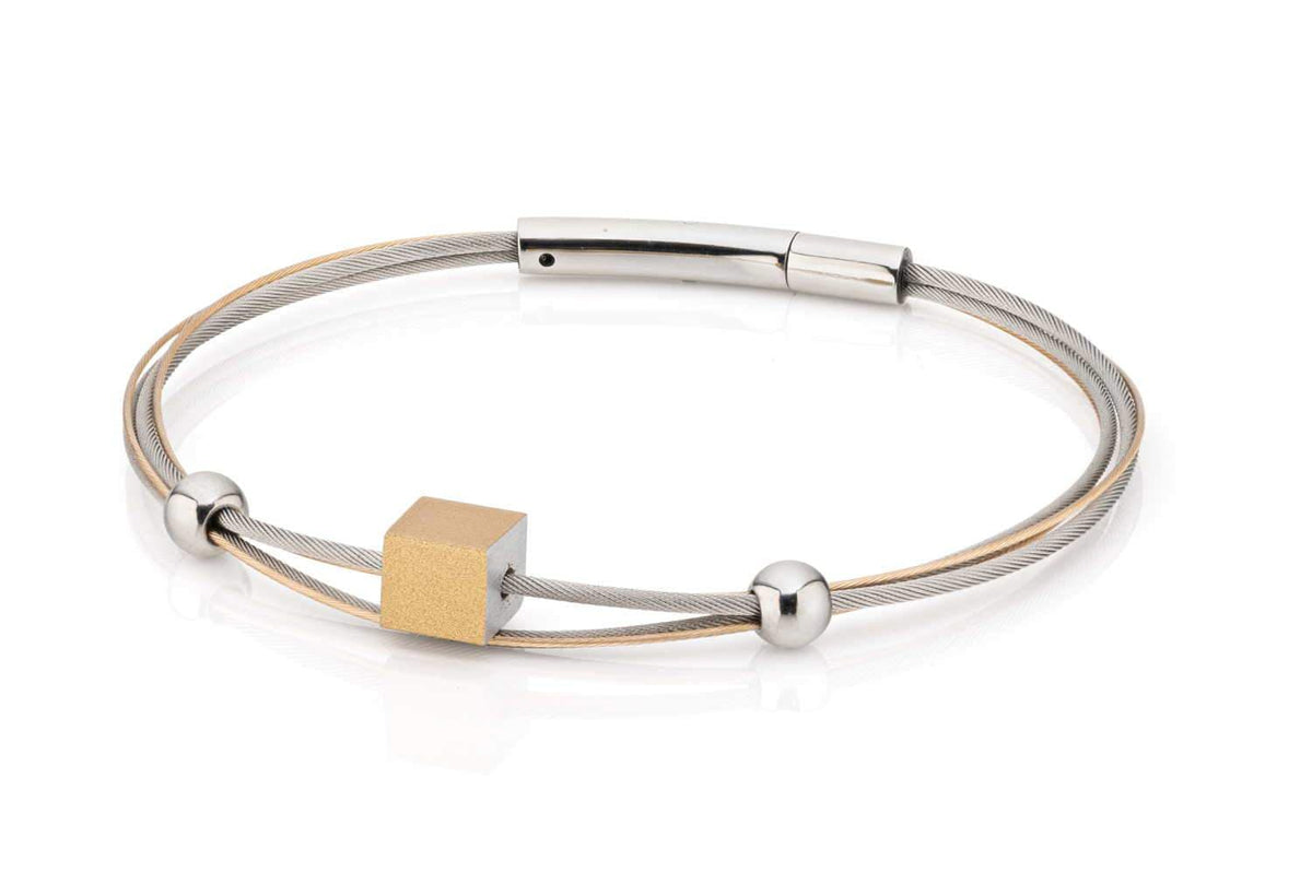 Pulsera dorada con un cubo y dos esferas plateadas en un diseño moderno.