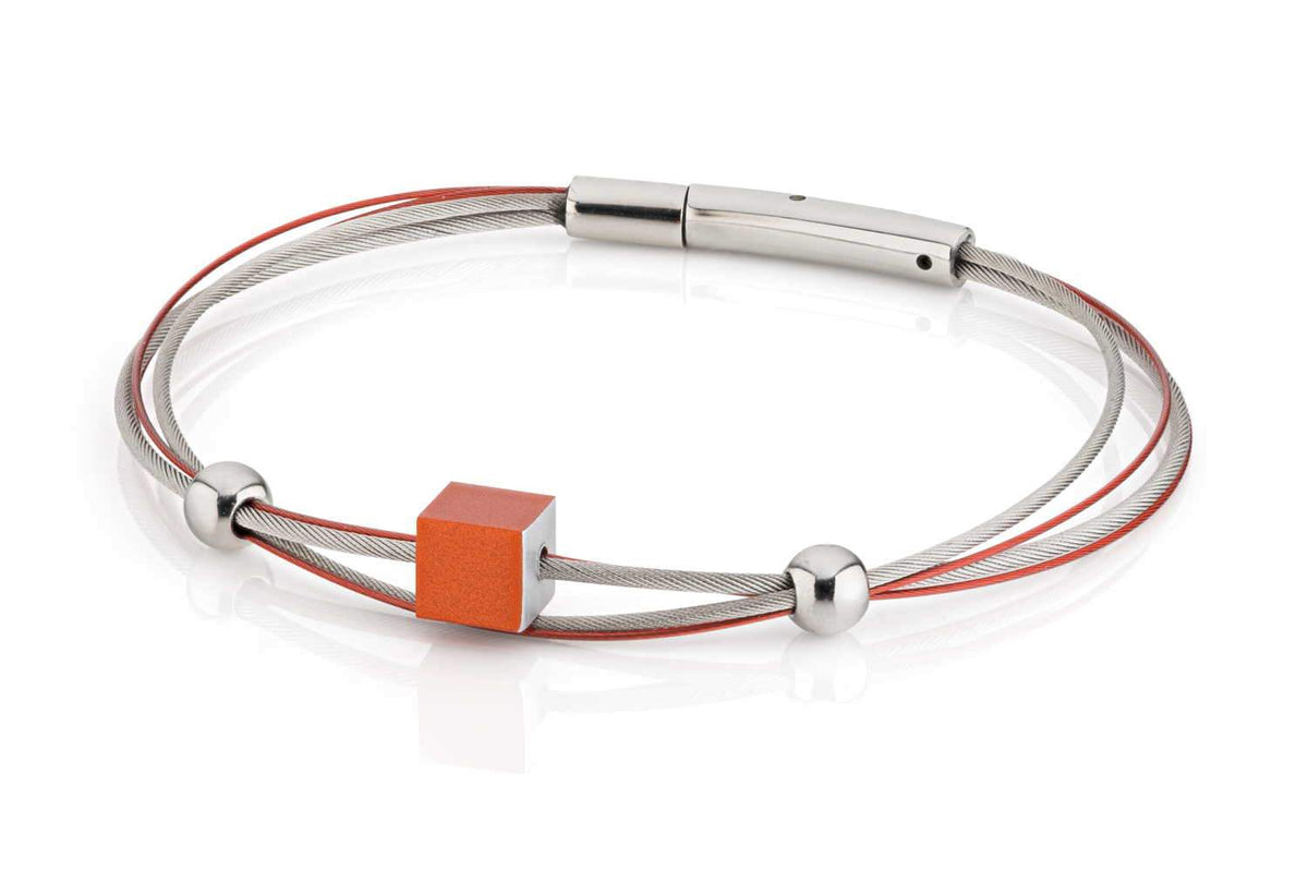 Pulsera con un cubo naranja y esferas plateadas, hecha de cables metálicos.