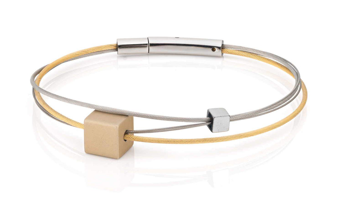 Pulsera de cuero amarillo con detalles metálicos en plata y un cubo dorado.