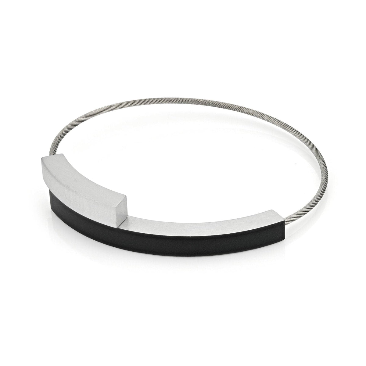 Pulsera con dos arcos, uno plateado y otro negro, sobre una base metálica.