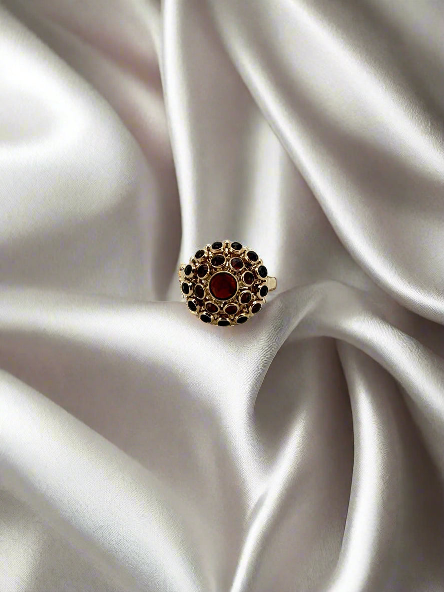 Anillo vintage de oro de 14k con granate central y piedras negras alrededor.