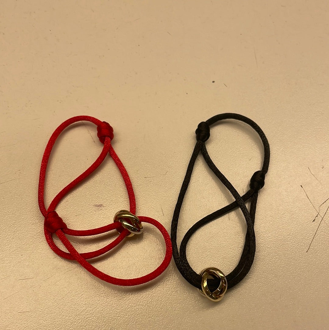 Pulseras de hilo rojo y negro con detalles dorados.