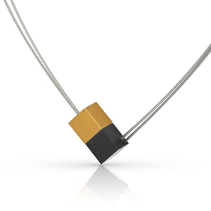 Collar con dos cubos, uno dorado y uno negro, sobre una cadena de acero inoxidable.