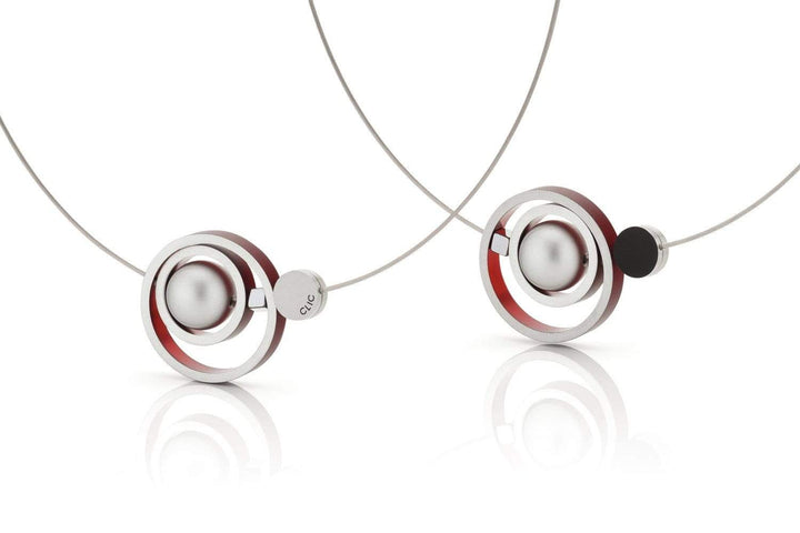 De Collier Ringen in elkaar Rood C187R oorbellen van CLIC Creations hebben elegante zilveren en rode cirkelvormige elementen op dunne draden. Ze zijn handgemaakt in Nederland, hebben een reflecterend oppervlak en tonen een eigentijds minimalistisch ontwerp met op maat gemaakte precisie.
