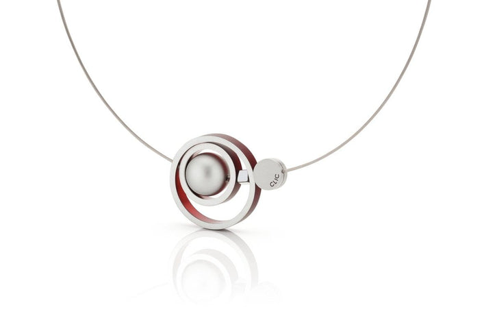 Ontdek de Collier Ringen in elkaar Rood C187R van CLIC Creations, een modern handgemaakt Nederlands sieraad met concentrische cirkels met een zilveren bol en een rode lus aan een strakke metalen ketting met een magneetsluiting.