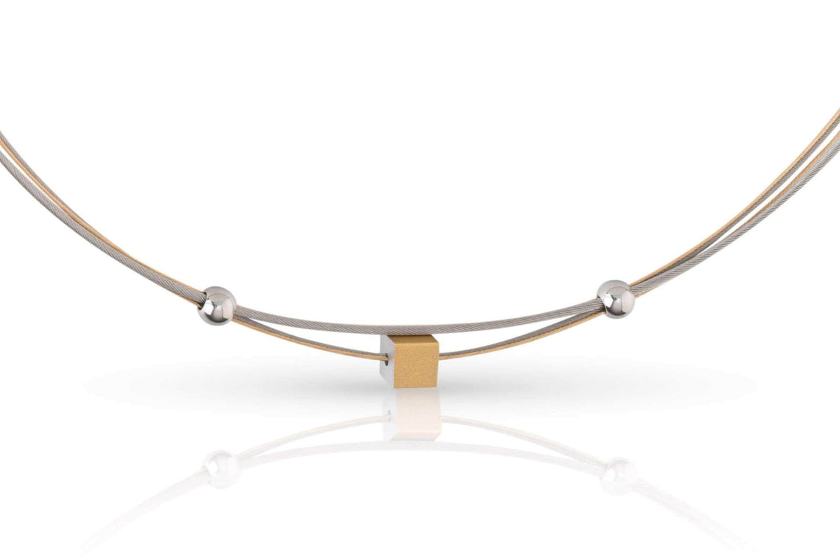 Collar dorado con un pequeño cubo y esferas plateadas en un diseño moderno.