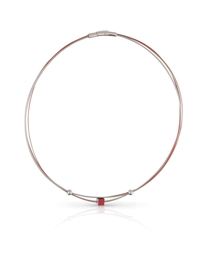 De CLIC Creations Collier Klein Kubusje Rood C230R is een minimalistische ketting gemaakt van chirurgisch staal, met een dunne ronde band met een klein rood accent, magnetische sluiting en twee decoratieve kralen, die prachtig een zachte schaduw werpen op een witte achtergrond.