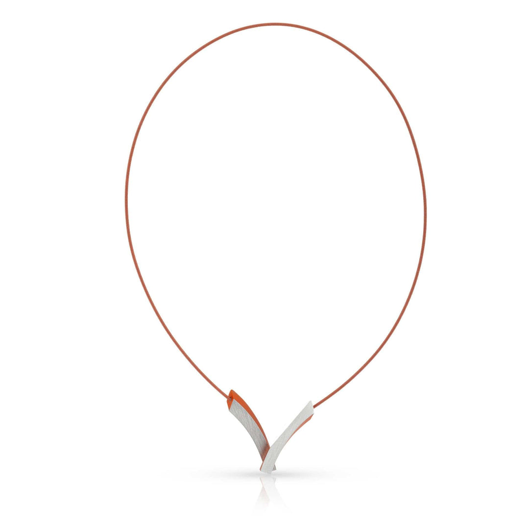 De Collier V-Bogen op elkaar Oranje C255O van CLIC Creations is een strak, modern Dutch design collier met een dun oranje koord en een geometrische zilveren hanger van kruisende rondingen. Het is voorzien van een magneetsluiting voor moeiteloos dragen.