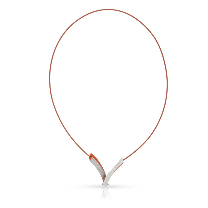 De Collier V-Bogen op elkaar Oranje C255O van CLIC Creations is een strak, modern Dutch design collier met een dun oranje koord en een geometrische zilveren hanger van kruisende rondingen. Het is voorzien van een magneetsluiting voor moeiteloos dragen.