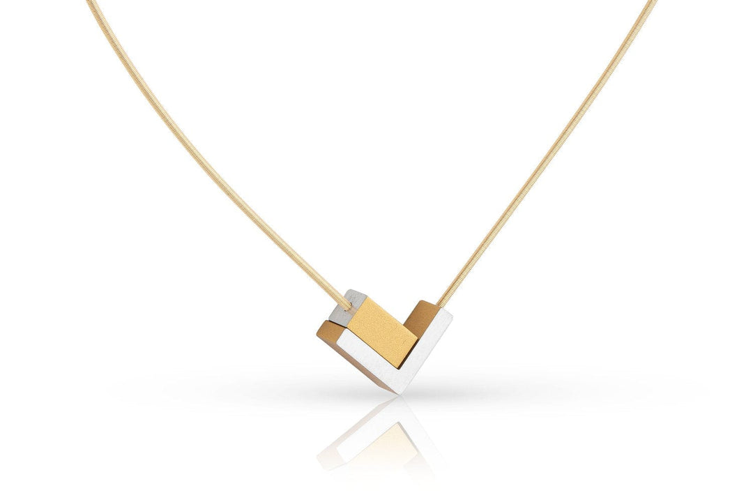 De CLIC Creations Collier V-tje met en rechthoekje Goud|Geel C256G heeft een gouden en zilveren geometrische hanger aan een edelstalen collier draad. Het V-vormige ontwerp biedt een strakke, moderne look, waarbij de hanger elegant hangt aan een dunne gouden ketting, die subtiel het licht eronder reflecteert.