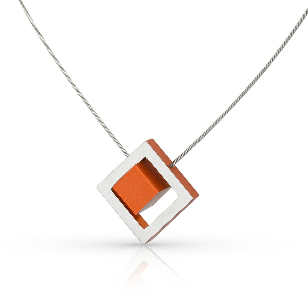 De Collier Kubus in vierkant C25O oranje van CLIC Creations is een moderne, handgemaakte Nederlandse ketting met een oranje vierkant in een gekanteld zilveren vierkant op een edelstalen collier met magnetische sluiting.