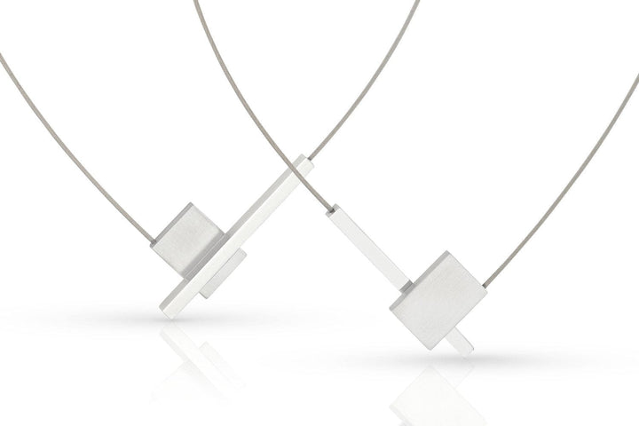 De Collier V-vorm met staafje C261 van CLIC Creations heeft een minimalistisch design met een geometrische rechthoekige hanger aan een dunne ketting en een makkelijke magnetische sluiting, afgebeeld op een witte achtergrond. Dit unieke stuk is handgemaakt in Nederland.