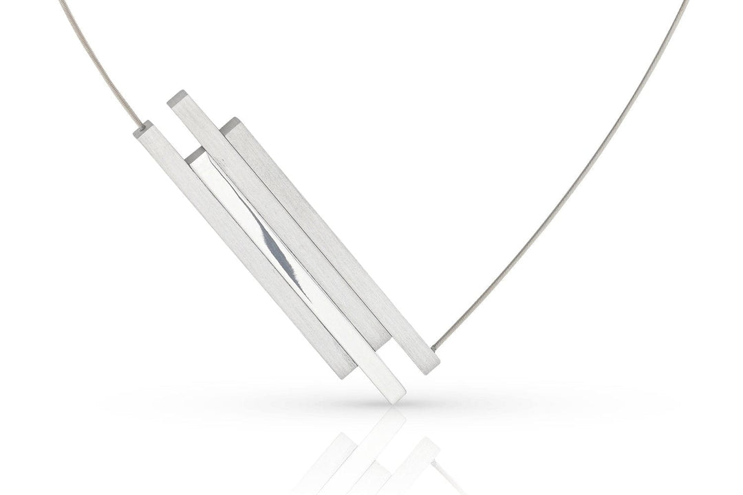 De C264-ketting van Clic Creations heeft een minimalistisch ontwerp met drie dunne, rechthoekige zilveren staafjes die aan een fijne ketting zijn bevestigd. Hierdoor ontstaat een geometrische en eigentijdse look tegen een witte achtergrond.