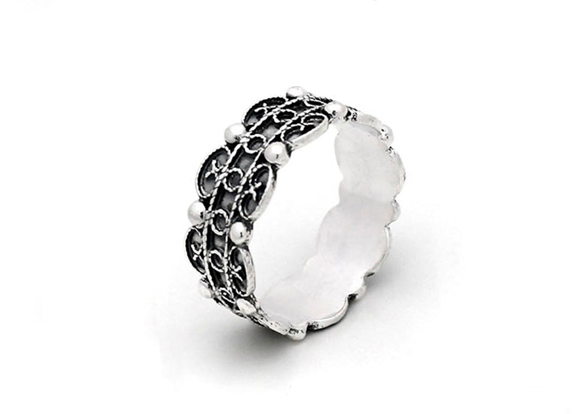 Anillo de plata con diseño de filigrana y detalles redondeados.