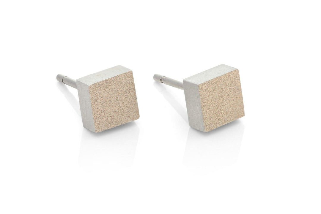 De Oorsteker Klein vierkant Goud O37G van CLIC Creations bestaat uit twee vierkante oorstekers met een geborstelde metalen afwerking op een witte achtergrond. Deze oorbellen tonen hypoallergene eigenschappen, een minimalistisch ontwerp met gladde randen en reflecterende oppervlakken die in elk handgemaakt detail een uniek design belichamen.